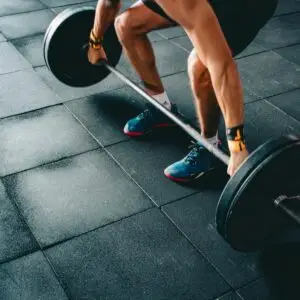 Young man lifting a heavy barbell during an intense indoor gym workout.